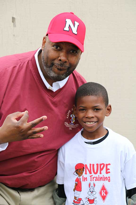 Kappa Alpha Psi Eta Chapter member with young boy at the tailgate prior to the UNL Red and White Spring Game tailgate at the Malone Center