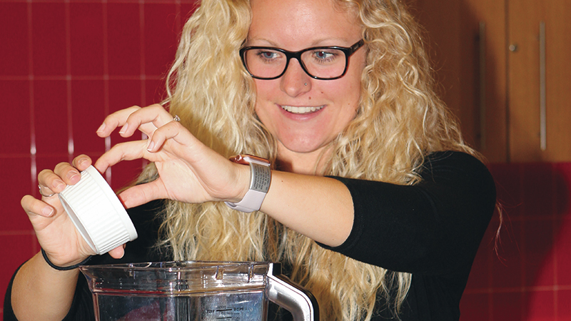 Female student adding yogurt to a blender in the Wellness Kitchen located in the Recreation and Wellness Center at the University of Nebraska-Lincoln