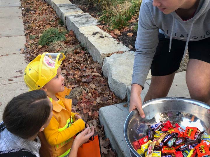 A child dressed as a firefighter selects candy.