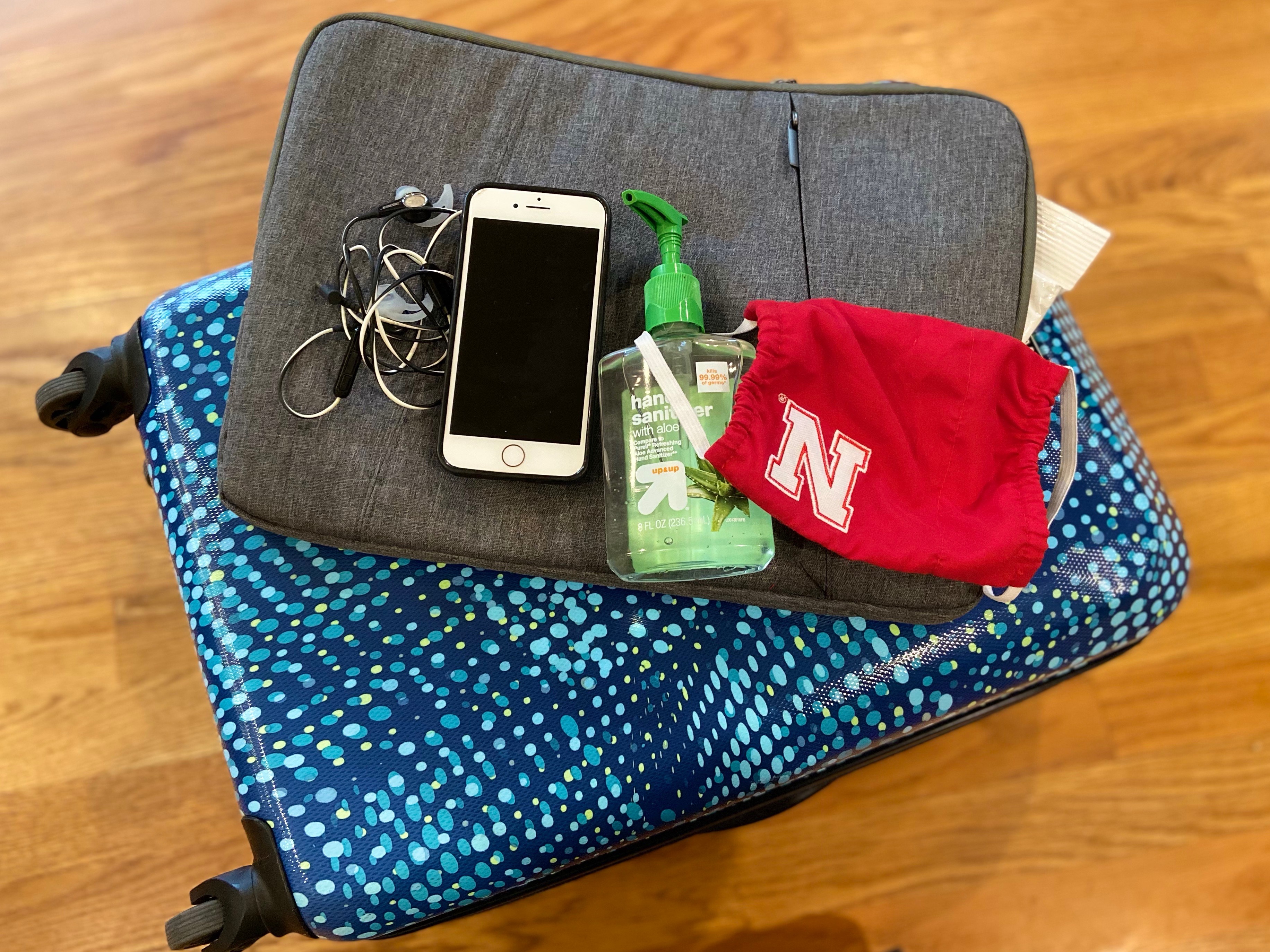 Phone, hand sanitizer, mask, suitcase -- ready for travel