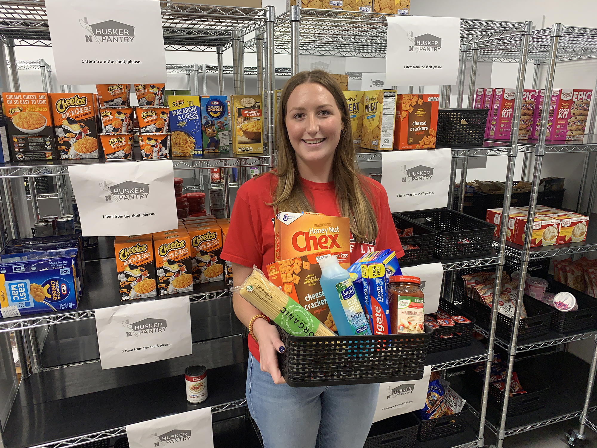 Husker Pantry graduate assistant Emilee Smith holds a basket of personal care and food items that are commonly-requested by University of Nebraska–Lincoln students. [Christopher Dulak | Student Affairs]