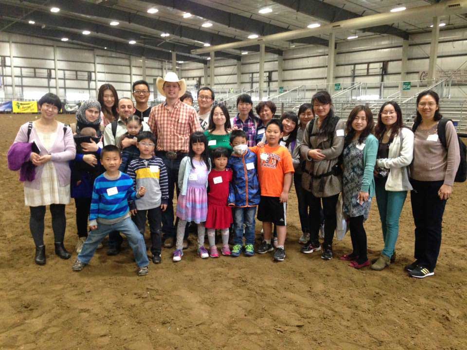 International students and family members visit with a cowboy to learn how the rodeo events work.