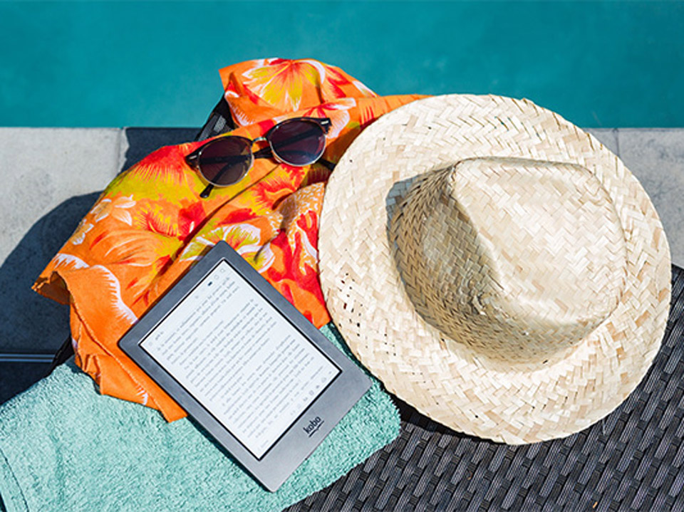 E-reader, hat, glasses and towel lay poolside