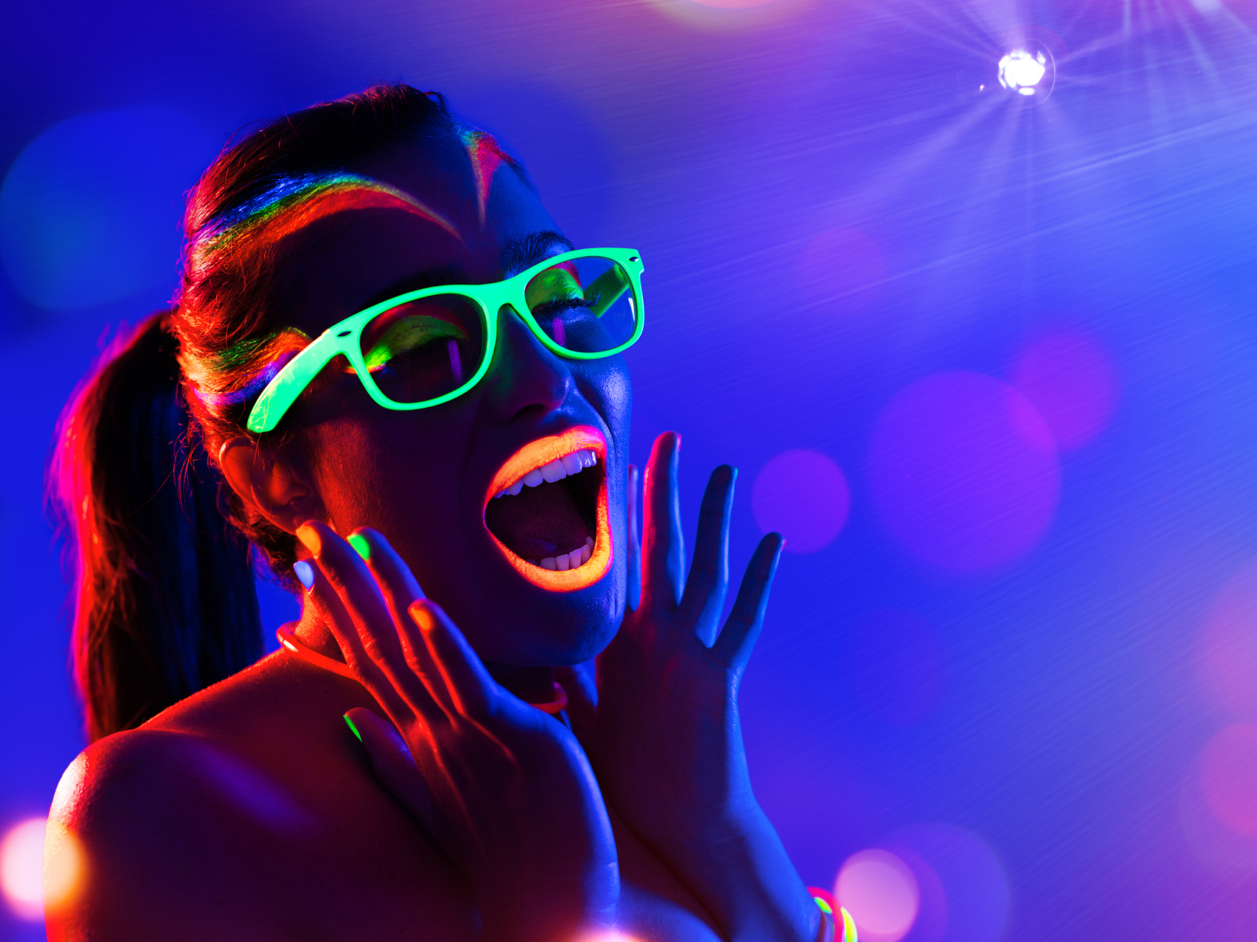 Woman screaming with glow-in-the-dark glasses. 