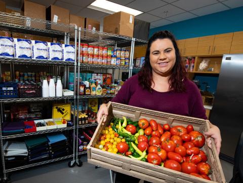 Graduate student Morgan Smith displays a tote of fresh vegetables available at the Husker Pantry. The on-campus food pantry helps more than 120 students per week secure free food and hygiene items. 