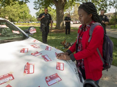 Elizabeth Uwase, a junior integrated science major from Rwanda, affixes her "Use Your Voice" pledge to a police car during the Sept 10 Cover the Cruiser event on East Campus. More than 75 students, faculty and staff made a pledge to stand up to sexual violence in the first day of the initiative.