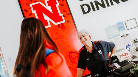 Nebraska's Lory Erving chats with a student at the Cather Dining register. Erving, a native of Hazel, South Dakota, has worked at the university for 35 years. She moved to Lincoln in 1985 after graduating from South Dakota State University with a bachelor's degree in music.