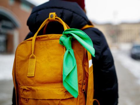 A student displays a green bandana tied to their backpack - a symbol of the Green Bandana project.