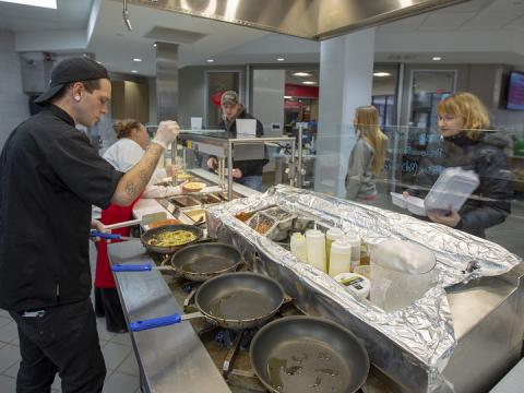 Samuel Klein, a dining service associate, prepares fresh fettuccine alfredo for Erin Bauer (right) at the World's Fare station in the new East Campus Dining Facility. The renovated space is part of a larger project that will offer three dining options in the Nebraska East Union. 