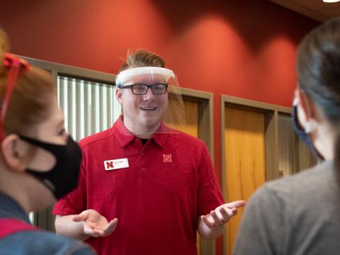 David Strang, an events associate with Academic Services and Enrollment Management, wears a face shield from Nebraska Innovation Campus while visiting with fellow Huskers. The face shields will be distributed to offices and colleges across campus to support students who are deaf or hard of hearing.