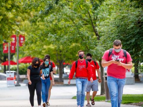 Students walk across campus while wearing face coverings