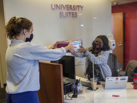 A student desk attendant helps a Husker at the Welcome Desk inside University Suites. [Mike Jackson | Student Affairs]