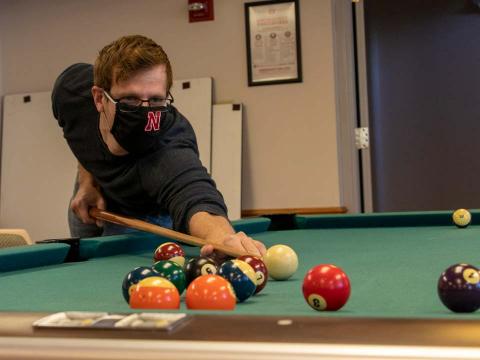 Jon Haag plays pool with friends during a game night following a Collegiate Recovery Community meeting at Husker Hall.