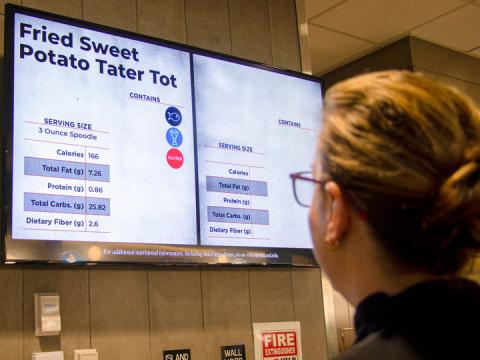 Staff member views the menu board in the Cather Dining Center.