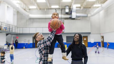 Ben Bentzinger, a senior in criminal justice, and Francisca Lawson Tettevie a graduate student in human sciences, help Journey shoot a basket at the Malone Center. [Craig Chandler | University Communication and Marketing]