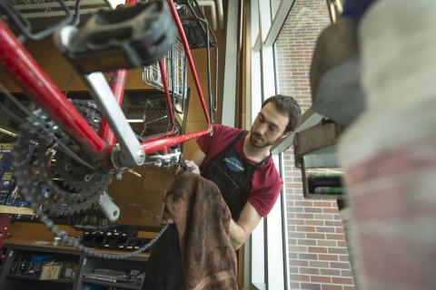 Paul Gebers, a student employee at the Outdoor Adventures Center bike shop, works on a chain as part of a basic bike tune-up.