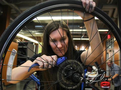 Female bicycle mechanic works on a tire inside the Outdoor Adventure Center's bike shop.
