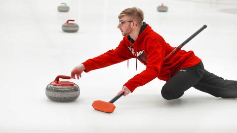 Brett Johnson slides a curling stone Jan. 20, 2024 during the club team's bonspiel at the Breslow Ice Hockey Center. [Taryn Hamill | University Communication and Marketing]