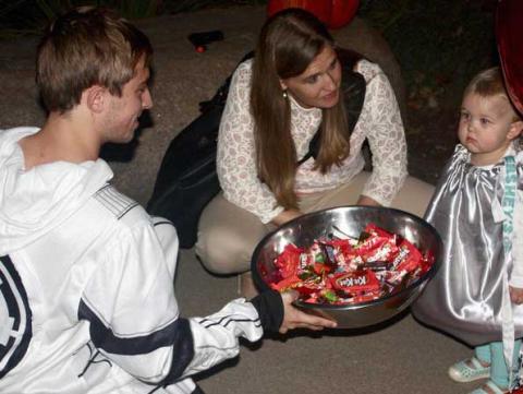 Greek member dressed as a storm trooper offers candy to a child dressed as a Hershey's kiss.
