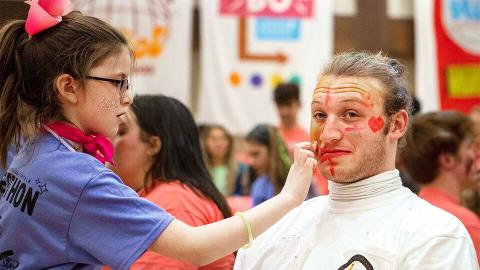Sam DeZube, senior in finance, has his face painted by Parker Malzen before performing with his band at HuskerThon 2023. The event, which was held Feb. 25 in the Nebraska Union, raised nearly $120,000 for Children’s Hospital and Medical Center. [Blaney Dreifurst | University Communication and Marketing]