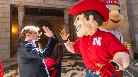 Paul Pechous (left), incoming president of the Association of Students of the University of Nebraska, high-fives Herbie Husker at the Nebraska State Capitol. Employees, alumni and supporters of the University of Nebraska–Lincoln and the NU system showed up to the capitol for April 5’s “I Love NU” Day. [Craig Chandler | University Communication and Marketing]
