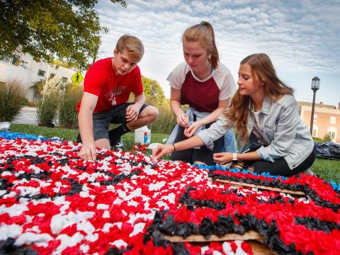 Students use napkins and glue to create lawn displays as part of the 2018 Homecoming festivities.