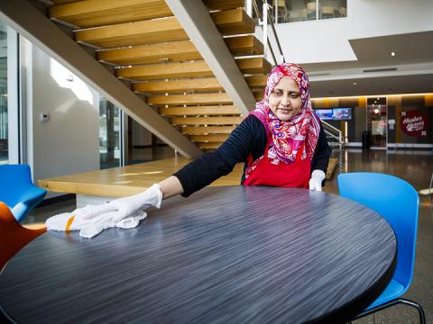 Kishuar Sultana, a University Dining Services employee, cleans tabletops in Nebraska's Willa S. Cather Dining Complex. 
