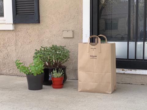 A paper grocery bag sits outside a house's door. (Christopher Dulak | UNL Student Affairs)