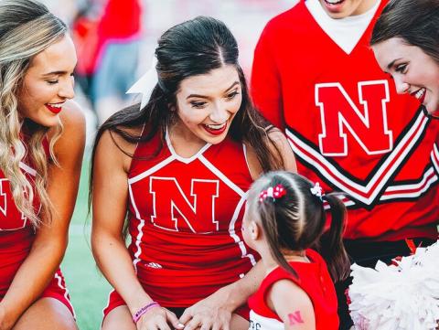 Kaela Meyer (center) interacts with a young fan at a Husker football game, prior to the COVID-19 pandemic. [Husker Athletics]