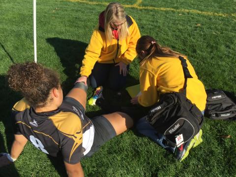 Two athletic training students with the Injury Prevention & Care program assess an injury on a female soccer player.