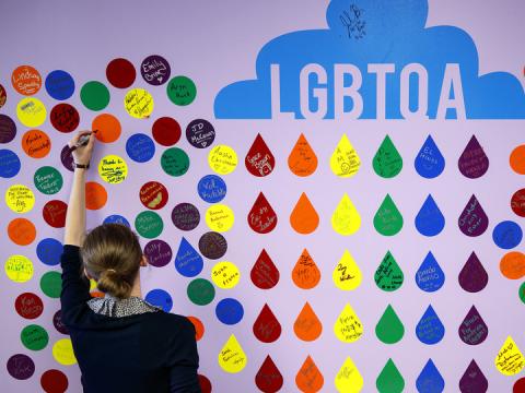 A student adds a signature to the Wall of Fame inside the LGBTQA+ Resource Center.