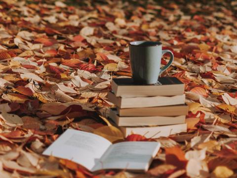 Stack of books with coffee sitting in the leaves