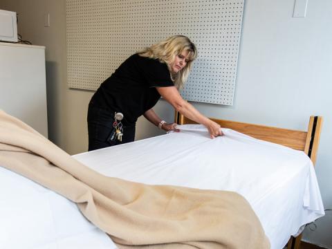 Mary Kavan, assistant facilities manager in Selleck Facilities Operations, prepares a bed inside Neihardt Hall. The university will begin using the Piper wing of Neihardt as a quarantine facility for its students.