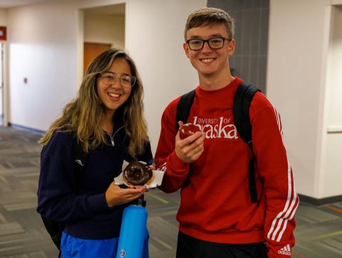 Students in residence hall hold donut and apple as snacks from Resident Appreciation Week activities.