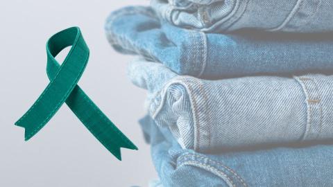 Denim jeans stacked in a pile next to a teal ribbon, representing Sexual Assault Awareness Month.