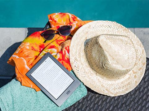 E-reader, hat, glasses and towel lay poolside