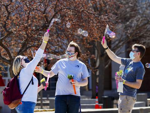 Students (from left) Samantha Moore, William Roarty and Jace Armstrong let the wind do the work as they blow bubbles outside the Nebraska Union during Spring Breakout on March 29. [Craig Chandler | University Communication]
