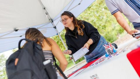 Husker Vote Coalition member explains to a student how to register to vote at a voter registration table on campus.