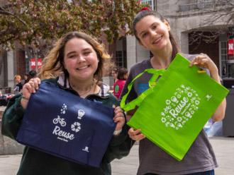 Rachel Summers and Kat Woerner, EarthStock co-chairs, show off reusable bags given out by the Office of Sustainability at EarthStock’s Block Party.