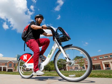 A student rides a Bike LNK bicycle through Meiers Common on the campus of the University of Nebraska-Lincoln.