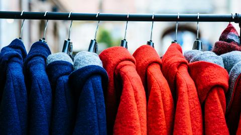 group of blue and red winter coats on hangers on a clothing rack. [image: markus spiske | unsplash]